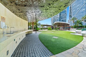 A modern outdoor area with a pool, a covered seating area, and a well-maintained lawn.