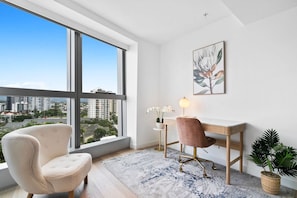 A modern room with a large window, a desk, a chair, and a potted plant.