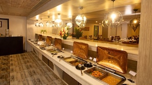 Een buffet met verschillende food stations, een houten plafond en moderne, bolvormige lampen.
