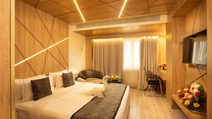 Een hotelkamer met een groot bed, een bureau, een stoel, een televisie en een bloemstuk.
