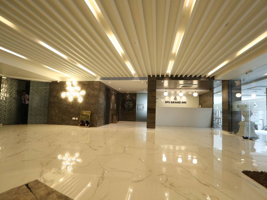 A spacious lobby with a polished marble floor, a reception desk, and a modern ceiling design with linear lighting.