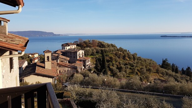 Un pueblo costero con arquitectura tradicional, vista despejada al mar y un paisaje montañoso.
