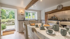 A modern kitchen with white cabinets, a brick accent wall, and a dining area with a table set for two.