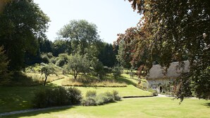 A grassy area with a stone house and a pathway leading to it.