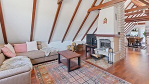 Un salón tipo loft con vigas de madera a la vista, una chimenea y una zona de estar acogedora con sofá y mesa de centro.