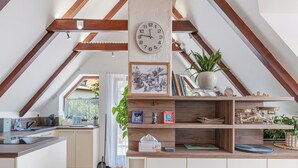Una cocina con techo de madera, un reloj y ventana con vistas a un jardín.