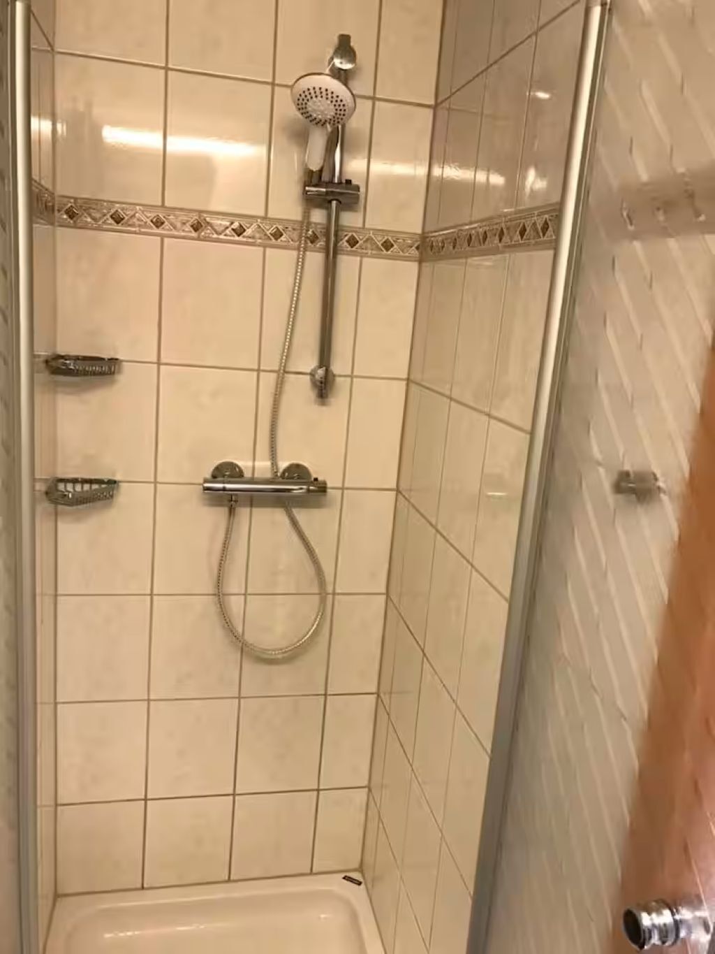 A shower with a handheld showerhead and a handheld basin.