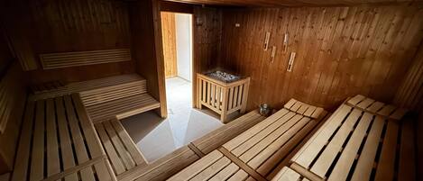 A sauna room with wooden benches and a small heater.