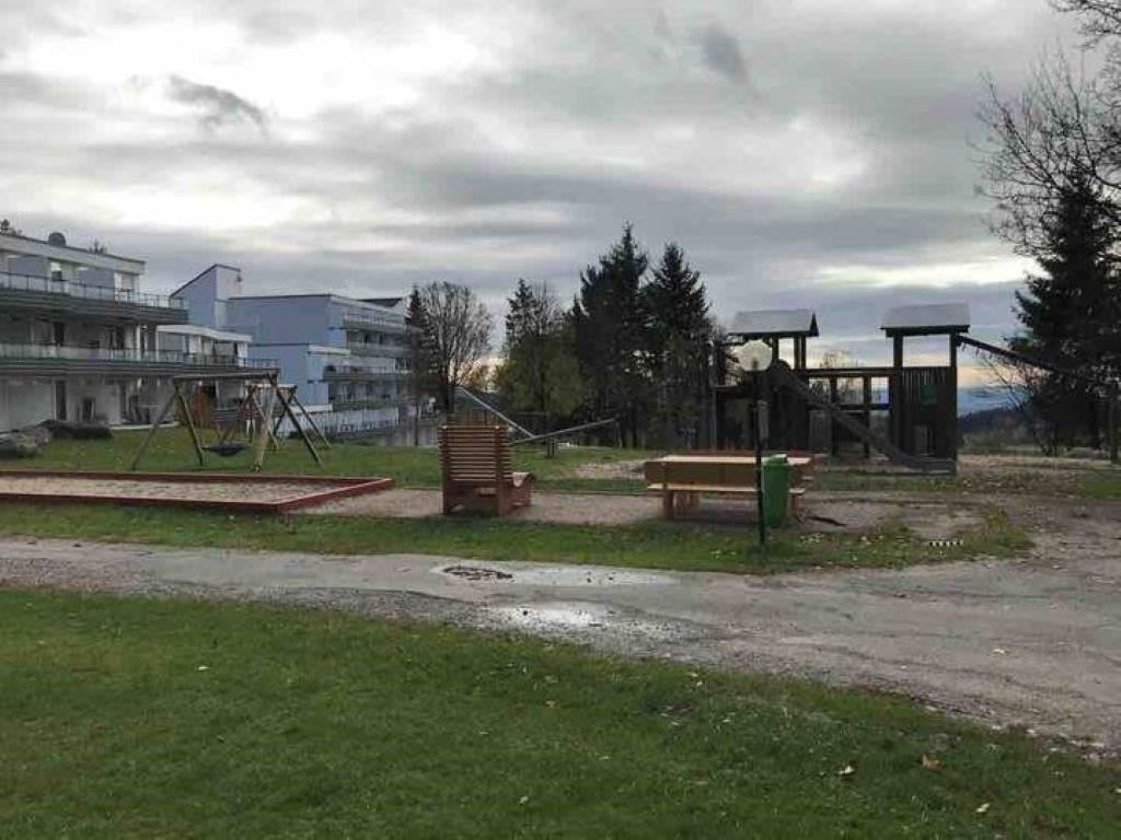A park with a swing set, benches, and a gazebo.