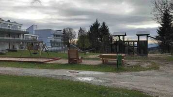 A park with a swing set, benches, and a gazebo.