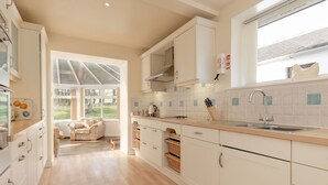 A modern kitchen with white cabinets, a wooden countertop, and a large window providing natural light.