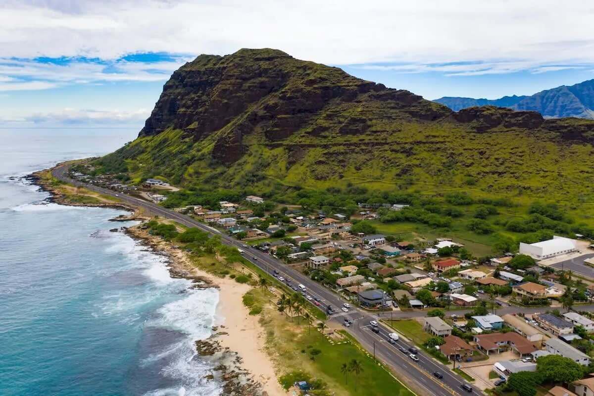 A coastal town with a prominent mountain, a beach, and a road running along the coast.
