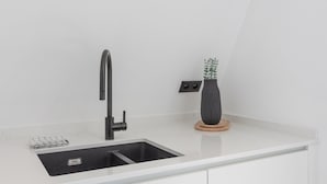 Una cocina moderna con un grifo negro, una encimera blanca y una planta en maceta.