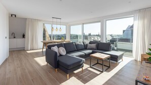 Una sala de estar moderna con un sofá modular, una mesita y vistas de la ciudad a través de amplios ventanales.