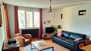 A modern living room with a leather sofa, a wooden coffee table, and a television on a stand. - Le Genève-Parking Garage & Balcony-air-conditioned (Ornex)