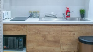 Une cuisine moderne avec des meubles en bois, un évier en acier inoxydable et une poubelle.