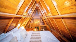 An attic bedroom with wooden walls and a sloped ceiling.