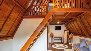 A spacious attic room with a wooden staircase, a sofa, and a coffee table.
