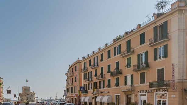 Une vue de rue avec un restaurant appelé « Cavallino Bianco » et un bâtiment historique en arrière-plan.