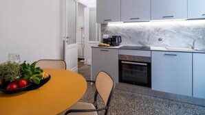 Une cuisine moderne avec des meubles gris, un plan de travail en marbre et un four encastré.