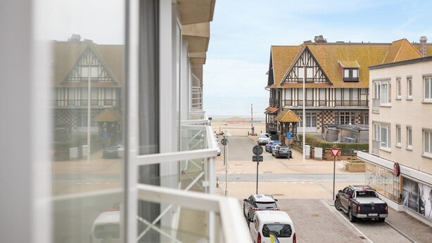 A coastal street with traditional half-timbered houses, a sandy beach in the background, and parked cars. - Seastar 0202 met garage (NIEUWPOORT)