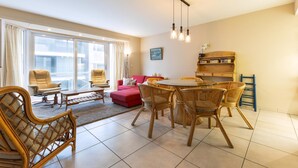 A modern living room with a dining area, large windows, and a view of the city. - Seastar 0202 met garage (NIEUWPOORT)