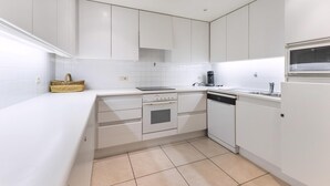 A modern kitchen with white cabinetry, a built-in oven, a dishwasher, and a coffee maker. - Seastar 0202 met garage (NIEUWPOORT)