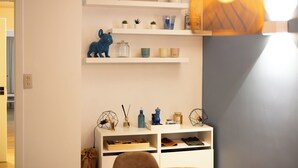 Ett rum med vita hyllor där olika dekorativa föremål visas upp, och en vit förvaringsenhet med skor.