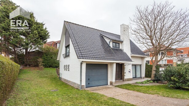 A single-story house with a grey tiled roof, a garage, and a well-maintained lawn.