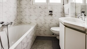 A bathroom with a bathtub, toilet, and sink.