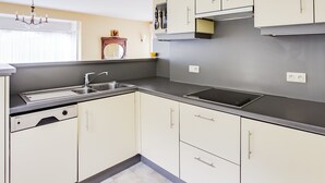 A modern kitchen with white cabinets, a stainless steel sink, and a built-in oven.