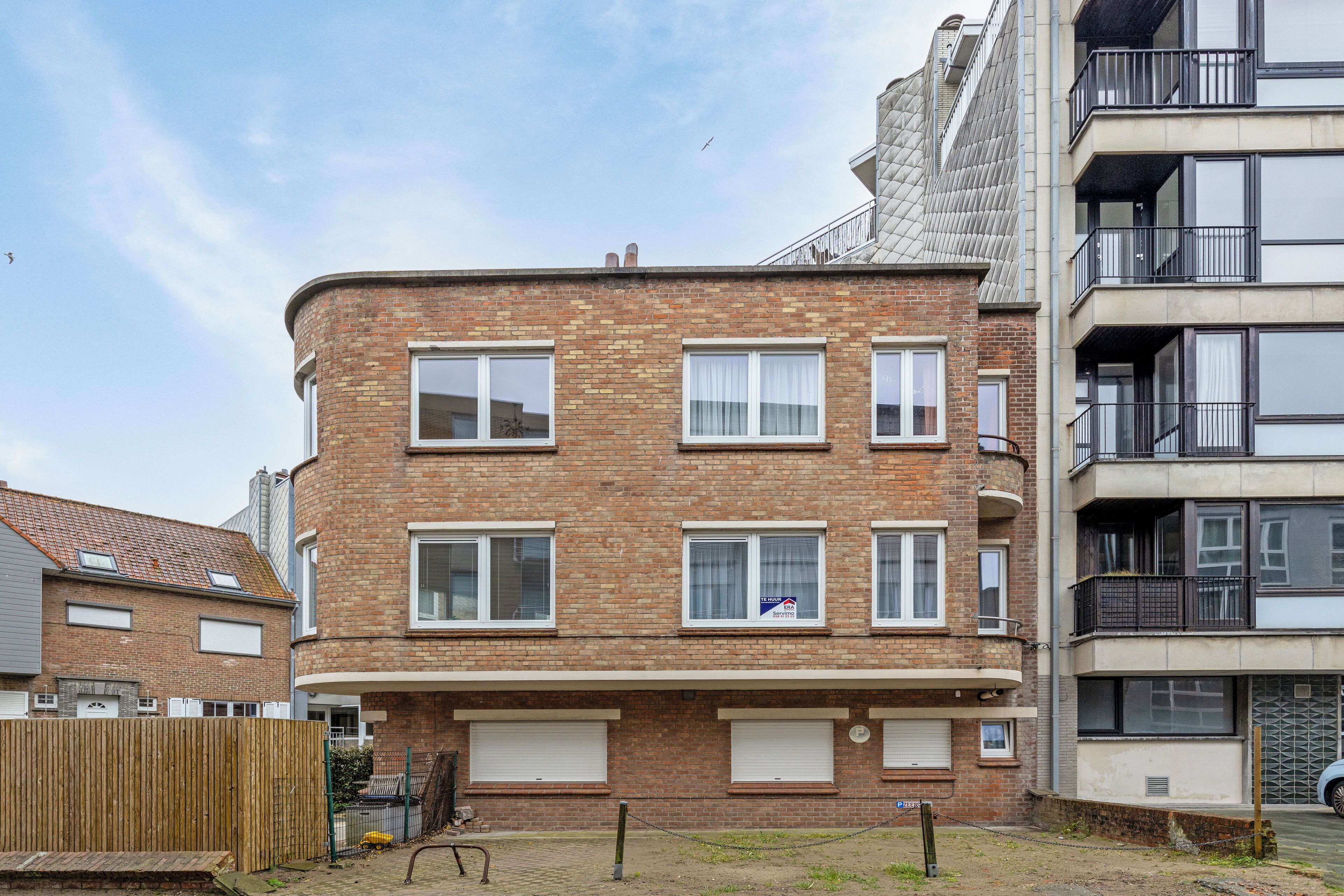 A multi-story residential building with a brick facade, multiple windows, and balconies.