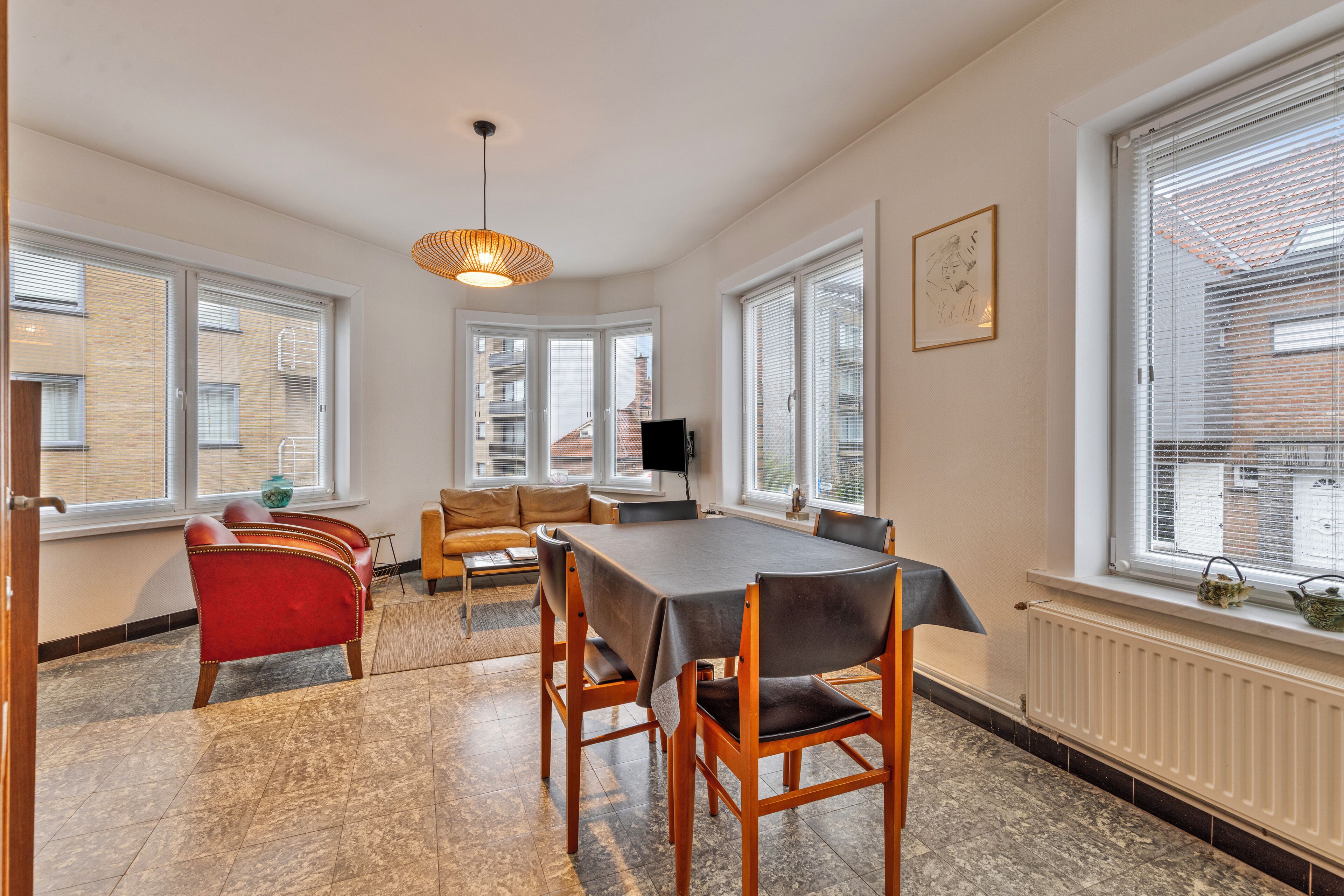 A dining area with a table and chairs, a sofa, and a television.