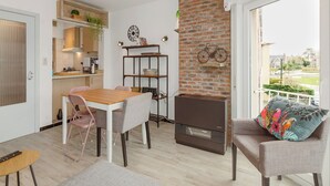 Una sala moderna con comedor, una pared de ladrillo y vistas al exterior.