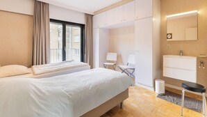 Een moderne hotelkamer met een groot bed, een bureau, een stoel, een kleine tafel, een spiegel en een raam met gordijnen.
