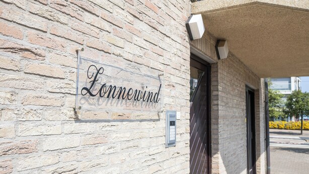 En byggnad av tegel med en skylt som visar texten ”Lonnewind”.