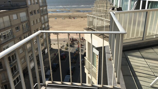 A view from a balcony overlooking a beach with a clear sky. - Gouden Boom 0618 + P* (Koksijde)