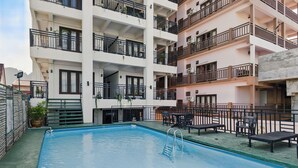 A multi-story residential building with a swimming pool, outdoor seating, and balconies. - Central Hotel Vang Vieng (Vang Vieng)