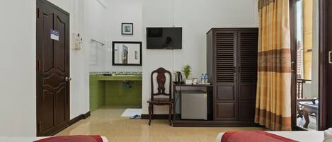Una habitación de hotel con dos camas, un escritorio, un televisor y un refrigerador pequeño.
