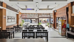 A spacious indoor dining area with multiple tables and chairs, a vending machine, and a view of the street outside. - Central Hotel Vang Vieng (Vang Vieng)