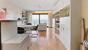 A modern, well-lit room with a dining area, a sofa, and a view of the beach. - 1 bedroom accommodation in De Panne (De Panne)