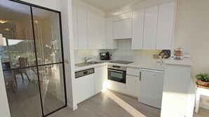 A modern kitchen with white cabinetry, a dishwasher, an oven, and a coffee maker.