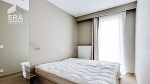 A bedroom with a bed, a radiator, and a window with curtains. - 3 bedroom accommodation in Koksijde (Koksijde)
