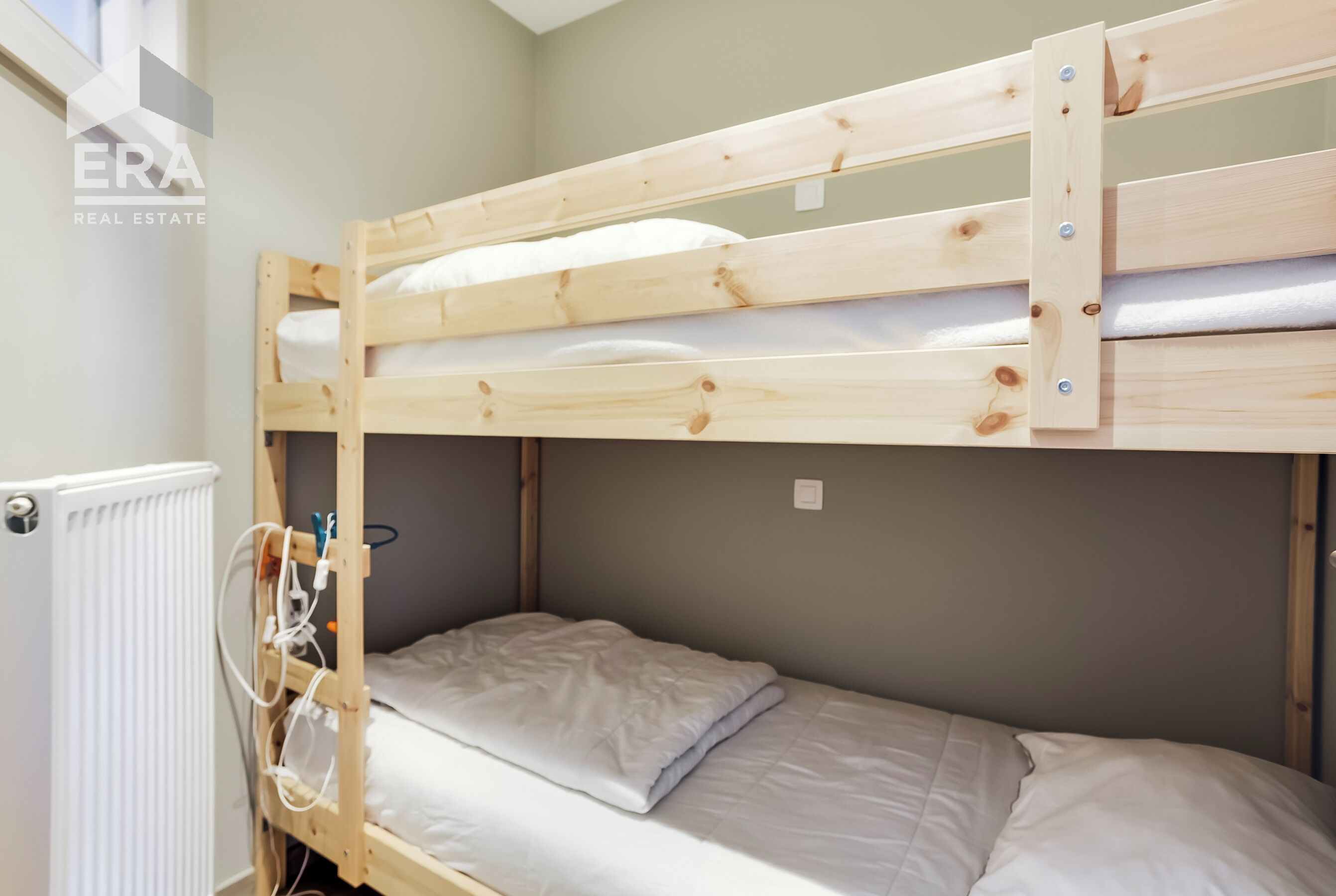 Una cama litera con estructura de madera y ropa de cama blanca.