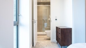 Un bagno moderno con box doccia in vetro, un water e un armadietto in legno.