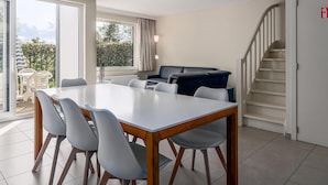 Un salon moderne comprenant une table à manger, des chaises, un canapé et un escalier.