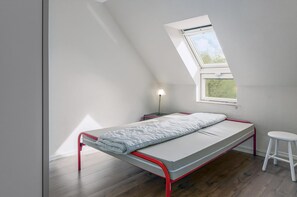 A small, single-bed room with a skylight, a bedside table, and a white stool. - 3 bedroom accommodation in Nieuwpoort (Nieuwpoort)
