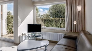 Un salon moderne avec un meuble TV en verre, un canapé et une table.