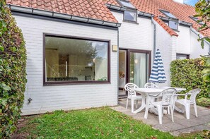 A house with a large window, a patio with a table and chairs, and a striped umbrella. - 3 bedroom accommodation in Nieuwpoort (Nieuwpoort)
