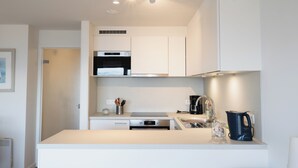 A modern kitchen with white cabinetry, a built-in oven, a coffee maker, and a sink. - 1 bedroom accommodation in Nieuwpoort (Nieuwpoort)